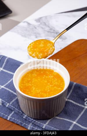 Goldener Hirse-Kürbisbrei garniert mit getrockneten Goji-Beeren Stockfoto