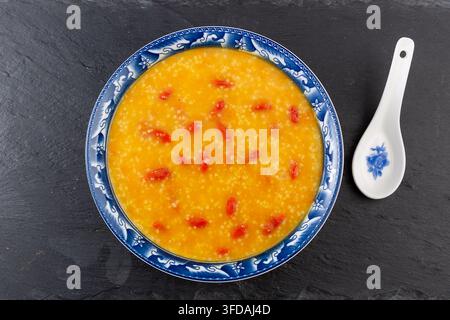 Goldener Hirse-Kürbisbrei garniert mit getrockneten Goji-Beeren Stockfoto