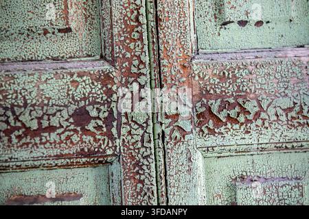 Abblätternde Farbe und verwitterte Textur an einer alten Holztür Stockfoto