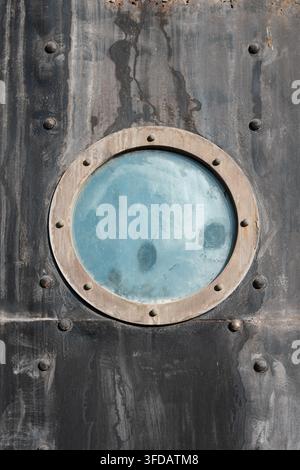 Wunderschöne professionelle Stockfotografie, die einen runden Stahlrahmen-Link an einer dunklen Eisenwand einfängt. Abstrakte Komposition über Schutz, Isolation, Stockfoto