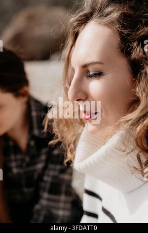 Frauenprofil Lockiges Haar friedliches Model mit roten Lippen und gestreiftem Pullover im Freien, das den sonnigen Herbstnachmittag genießt Stockfoto