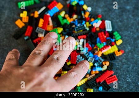 Eine Nahaufnahme einer Ansammlung von leuchtend farbigen Bauklötzen, die auf eine dunkle Oberfläche gefallen sind. Steht für Kreativität, Spiel und Konstruktion Stockfoto