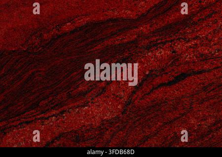 Nahaufnahme einer polierten roten Granitplatte mit diagonalen schwarzen Adern und gesprenkelter Kristallstruktur, eine natürliche Steinoberflächentextur für Innenarchitektur Stockfoto