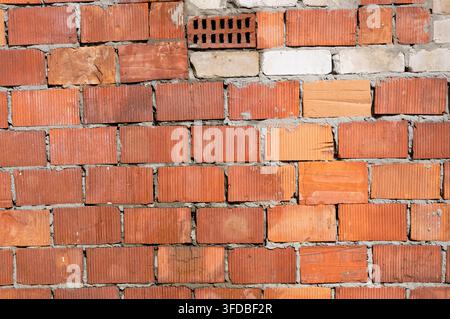 Alte verfallene Ziegelwandtextur als Hintergrund. Grob verlegte Ziegelwand aus alten rissigen Ziegelsteinen Stockfoto