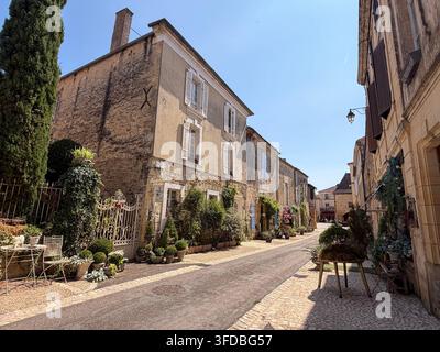 Traditionelle französische Dorfstraße mit historischen Steinhäusern, Fensterläden und Gärten in Beaumont-du-Périgord, Dordogne, Frankreich, 23. August 2026 Stockfoto