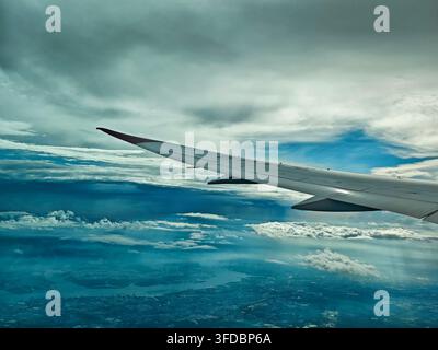 Singapur, Singapur - 2. Oktober 2025: Atmosphärische Luftaufnahme aus dem Flugzeugfenster zeigt den Flügel, der sich über geschichteten Sturmwolken erstreckt während eines Stockfoto
