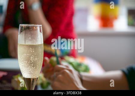 Glas mit sprudelndem Champagner oder Prosecco mit Bläschen im Fokus während der festlichen Weihnachtsessenvorbereitung zu Hause. Stockfoto