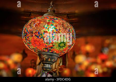 Eine handgefertigte Mosaiklaterne leuchtet sanft vor einem warmen, gedämpft beleuchteten Hintergrund. Stockfoto