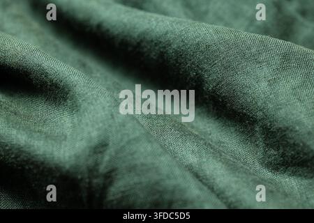 Grüner Stoff, der zerknitterte Textilwellen und eine weiche Textur zeigt Stockfoto