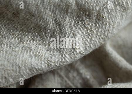 Leinenstoff, der seine gewebte Textur, natürliche Fasern und weiche beige Farbe zeigt Stockfoto