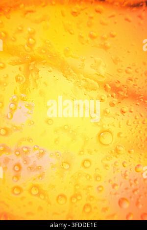 Wassertropfen glitzern auf einer Oberfläche, in Oberfläche mit Wassertropfen, aus einer Nahaufnahme-Perspektive, mit gelben, orangefarbenen Akzenten und frisch und v Stockfoto