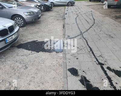Ein Außenparkplatz mit mehreren Fahrzeugen, die auf einer gemischten Oberfläche aus Kies und Ziegelpflaster geparkt sind. Im Vordergrund steht ein silberner BMW-Kombi mit einem Stockfoto