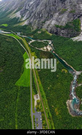 Drohnenfoto des Romboledentals nahe Eidet, Rauma, das einen gewundenen Fluss, Waldbedeckung, eine Autobahn und steile Kalksteinklippen zeigt. Stockfoto