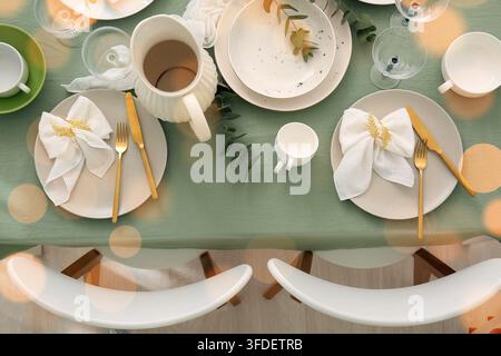 Gedeckter Tisch für ein Feiertagsessen, festliches Essen und Gastfreundschaft mit eleganten Gedecken und goldenem Besteck auf einer grünen Leinentischdecke Stockfoto