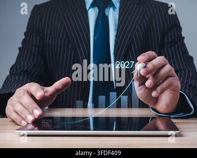 Geschäftsführer analysiert eine steigende Kurve von 2026 bis 2027 auf einem digitalen Tablet, Umsatzwachstum, Finanzprognose, strategische Planung und eine positi Stockfoto