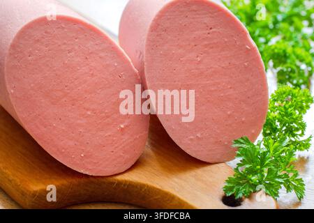 Nahaufnahme von zwei Hälften einer gekochten Wurst. Wurst mit Kräutern auf einem Schneidebrett. Stockfoto