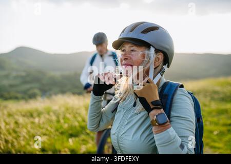 Aktives älteres Paar bereitet sich auf eine Radtour vor und setzt Helm auf. Stockfoto