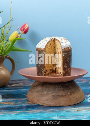 Traditionelle osteuropäische Paska, auch bekannt als Pasca, auf einem Glas-Kuchenständer präsentiert, mit einer entfernten Scheibe, um das weiche Innere zu enthüllen, umgeben von Stockfoto