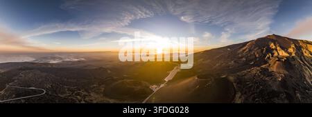 Luftaufnahme des Mount Etna bei Sonnenuntergang mit vulkanischen Hängen, kurvenreichen Straßen und goldenem Licht über der Landschaft in Catania, Sizilien, Italien. Stockfoto