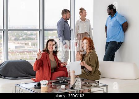 Glückliche diverse Kollegen, die im Büro über die Arbeit diskutieren Stockfoto
