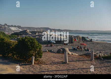 Leute entspannen sich an einem felsigen Strand bei Sonnenuntergang Stockfoto
