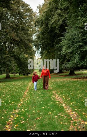 Mutter und Tochter gehen Hand in Hand durch den Herbstpark Stockfoto
