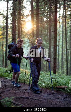 Paar wandert einen sonnendurchfluteten Waldweg entlang Stockfoto