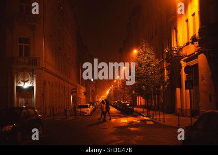 Paar geht auf einer nebligen europäischen Straße bei Nacht Stockfoto