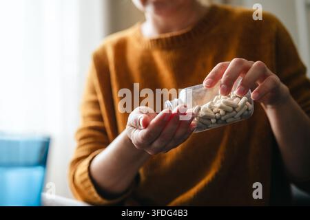 Frau gießt Ergänzungskapseln in ihre Hand Stockfoto