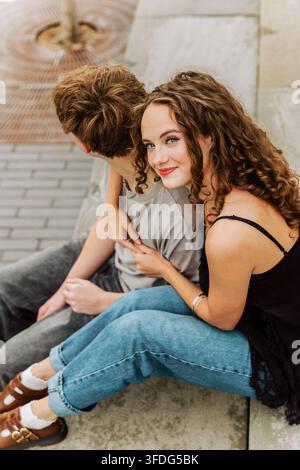 Junge Frau lächelt, während sie ihren Freund im Freien umarmt Stockfoto
