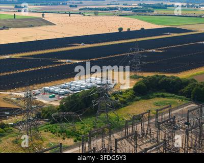 Luftaufnahme des National Grid Walpole Unterwerks und des angrenzenden Solarparks mit Strommasten und landwirtschaftlichen Feldern in Walpole, England, Vereinigtes Königreich. Stockfoto