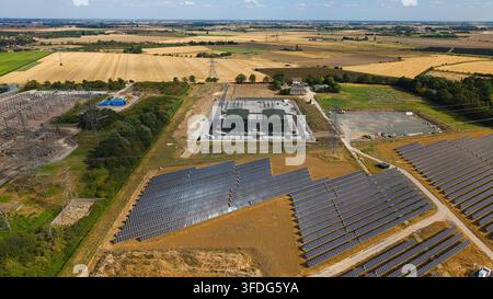 Luftbild der National Grid Walpole Unterstation und des angrenzenden Solarparks mit Reihen von Photovoltaikpanelen und Hochspannungsmasten in Walpole Stockfoto