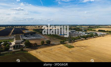 Luftbild der National Grid Walpole Unterstation, umgeben von landwirtschaftlichen Feldern, Solarpanelen und Stromleitungen unter einem blauen Himmel in Walpole, Engl Stockfoto