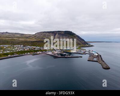 Luftaufnahme der Küstenstadt Grundarfjordur mit ihrem Hafen und dem markanten Berg Kirkjufell im Hintergrund unter einem bewölkten Himmel in Grunda Stockfoto