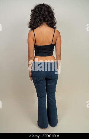Frau steht mit dem Rücken zur Kamera und präsentiert moderne Freizeitmode Stockfoto