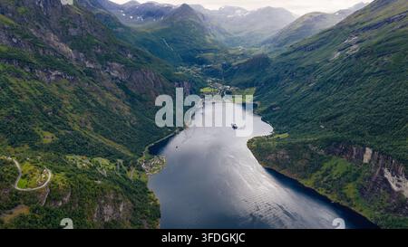 Drohnenperspektive eines tiefen Fjords mit verankerten Schiffen, umgeben von vertikalen Felswänden und dichtem grünem Wald. Stockfoto