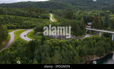 Drohnenperspektive der Highway-Infrastruktur, die sich durch borealen Wald mit Felsausläufern schneidet, moderne Brücke über eine tiefe Schlucht in der Nähe. Stockfoto