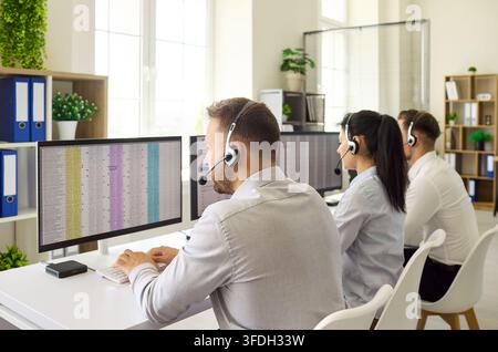 Konzentrierte Callcenter-Mitarbeiter, die Headsets an Monitoren in einem modernen Büro verwenden Stockfoto