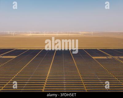Luftaufnahme der Arlington-Solaranlage mit Reihen von Photovoltaikpanelen und Windturbinen im Hintergrund unter einem klaren Himmel in Arlington, Oregon, Vereinigte Staaten Stockfoto