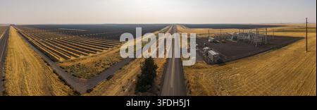 Luftaufnahme der Arlington-Solarfarm mit Reihen von Solarpanelen, einer Unterstation und einer Straße, die sich durch die trockene Landschaft in Arlington, Oreg, schneidet Stockfoto