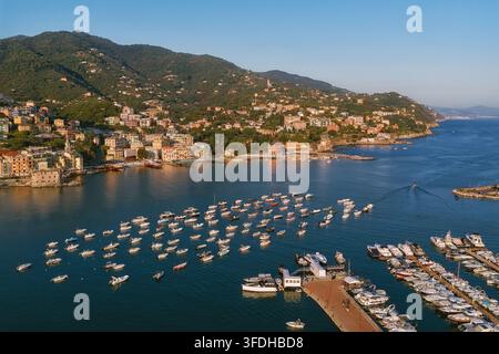 Luftaufnahme des Hafens in Rapallo, gefüllt mit kleinen Booten, mit der Küstenstadtarchitektur, üppigen grünen Hügeln und dem ruhigen Meer in Rapallo, Ligurien Stockfoto