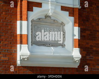 Das Schild „The Mansions Sloane Gardens“ an einem roten Backsteingebäude in Chelsea, London. Stockfoto