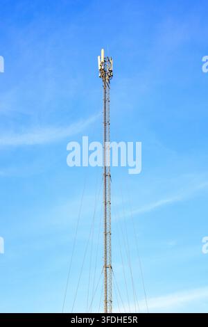 Vertikale Ansicht eines Stahlgitter-Mastturms, der durch Spannseile gesichert ist, vor einem hellblauen Himmelshintergrund. Konzept der digitalen Konnektivität, mobilen Breit Stockfoto