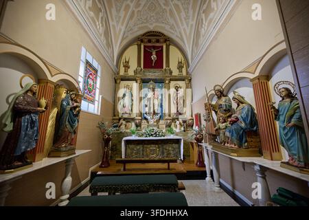 08-13-2026, La Baneza, Leon, Spanien Innenraum der Kapelle in La Baneza, Leon, mit einem reich geschmückten Altar, mehreren religiösen Skulpturen und einem Buntglasfenster Stockfoto