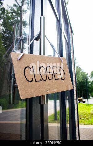 Schild „GESCHLOSSEN“ an der Willkommens­tür eines kleinen Ladens. Schließung eines lokalen Geschäfts. Inhaber sehen sich mit wirtschaftlichen Schwierigkeiten und Kundenverlust konfrontiert Stockfoto