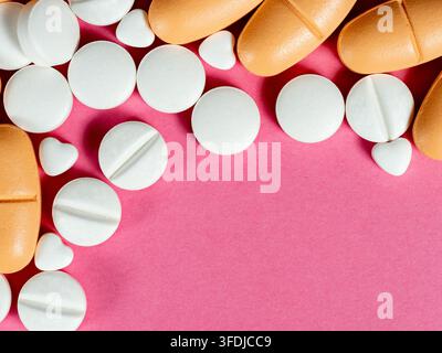 Weiße runde und orangefarbene längliche Tabletten, die auf einem rosa Hintergrund angeordnet sind, mit kleinen herzförmigen Pillen, die Medizin, Apotheke, Gesundheitsversorgung, Behandlung vermitteln Stockfoto