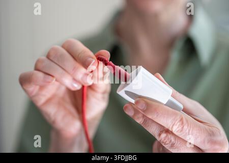 Frau beugt beschädigtes USB-Kabel in der Nähe des Ladegeräts und versucht, das instabile Telefonladen wiederherzustellen. Stockfoto