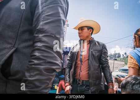 Chamula, Chiapas, Mexiko - 22. Oktober 2023: Blick auf einen jungen Mann, der einen Cowboyhut und eine Lederjacke trägt und auf einem lokalen Markt steht. Stockfoto