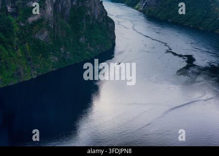 Luftperspektive eines tiefen norwegischen Fjords mit hohen Felskliffen, dichter Waldvegetation und Wasser, das Gezeitenstrommuster zeigt. Stockfoto