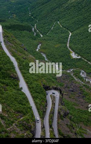 Drohnenperspektive einer sich windenden Bergstraße, die sich durch dichten grünen Wald schneidet, mit einer engen Spitzkehre, sichtbar ist eine Flussschlucht. Stockfoto